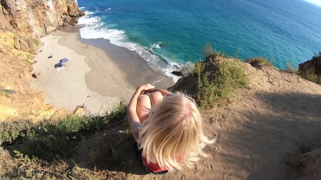 California travel destination concept. Lifestyle woman sitting on Pirates Cove promontory, a small cove on west side of Point Dume, Malibu coast in CA, United States. Californian West Coast.