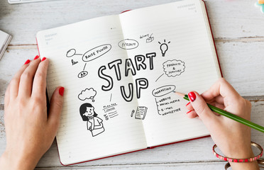 Young woman drawing start up in a notebook