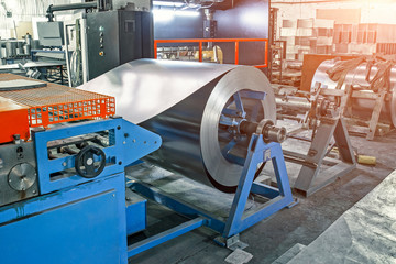 Worksop with machinery tools and equipment, rolls of galvanized steel for production metal pipes and tubes in factory