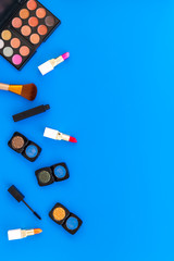Professional cosmetics set with palette of eyeshadows on blue background top view space for text