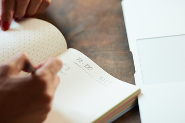 Woman writing to-do list in notebook.