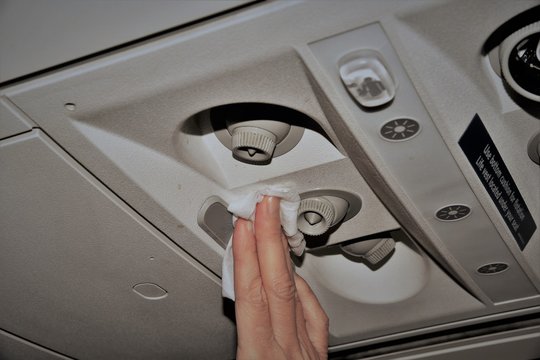 A woman in an airplane cleaning the air vents