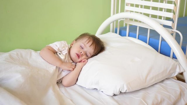 child sleeps in the hospital ward. concept of sleeping child. charming baby falls asleep on white bed in his bed .