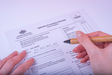 Filling Application form 1300t for Australian citizenship General eligibility on white surface. 