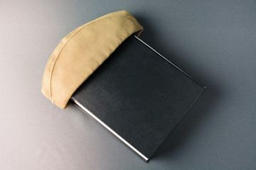 Green military cap is on the black book