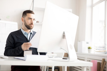 Naklejka premium Portrait of handsome bearded businessman using computer while working at desk in modern office, copy space