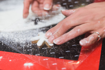 Woman decorates christmas gingerbread cookies with icing sugar glaze snowflake. Christmas gift, homemade gingerbread