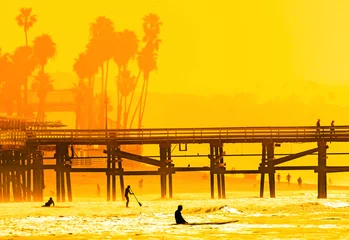 Fotobehang Surfers at San Clemente pier in the golden light of a summer sunset in Southern California © Don