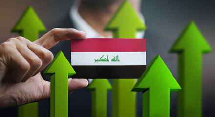 Nation Growth Concept, Green Up Arrows - Businessman Holding Card of Iraq Flag