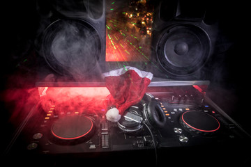 Dj mixer with headphones on dark nightclub background with Christmas tree New Year Eve. Close up...