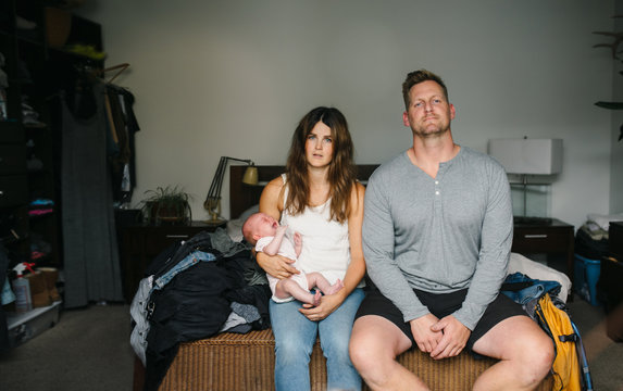 Stressed and tired new parents with screaming newborn baby in bed