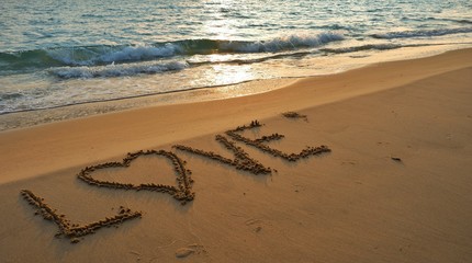 Marry concept, love heart shape handwriting on sand beach in sunset.
