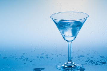 Blue theme image of water and ice cubes in a martini glass with backlight