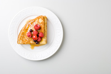 homemade pancakes with berries and honey on white palte
