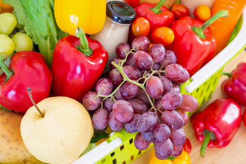 Fototapeta na wymiar Fresh fruits and vegetables in green shopping basket