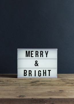 Lightbox with the message Merry & Bright on a wooden surface.
