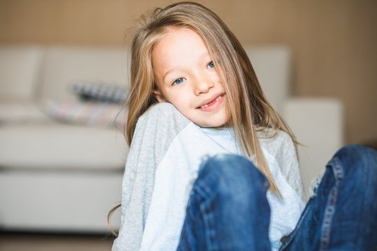 Cute little blond girl with missing front teeth looking at the camera smiling wide