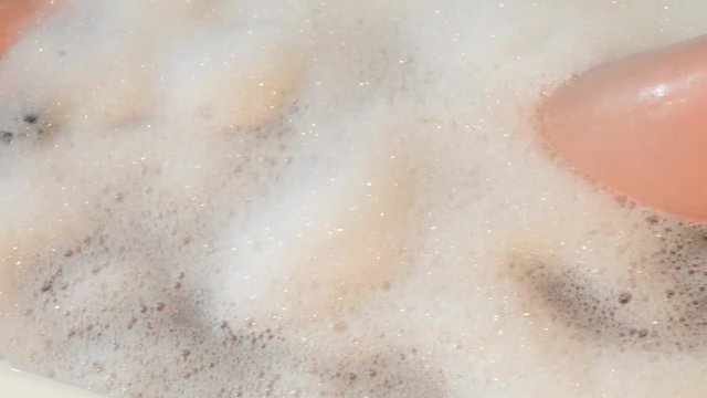 giovane donna si rilassa e gioca con la schiuma in una vasca da bagno
