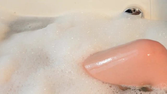 giovane donna si rilassa e gioca con la schiuma in una vasca da bagno