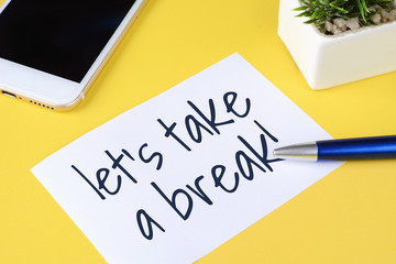 Paper card with "let's take a break" text and pen with phone