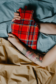 
a woman hugs a bag of hot water on the bed
