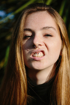 Pretty young woman with freckles showing her septum and lip piercings