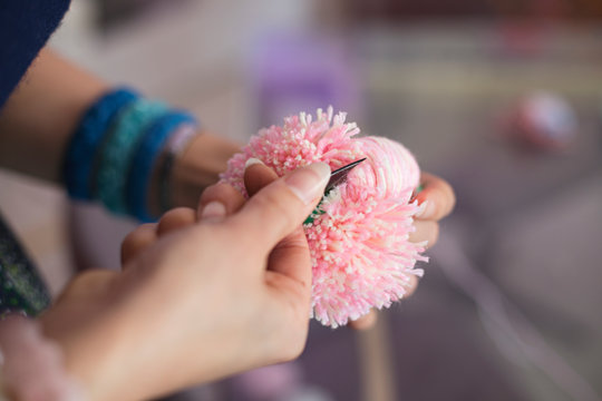 Hands making woollen pom poms