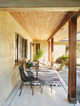 Bench with black and white pillows on front porch of home