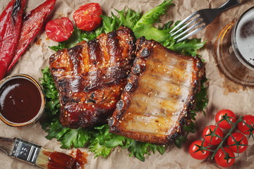 Closeup of pork ribs grilled with BBQ sauce and caramelized in honey on a paper. Tasty snack to beer. Top view. flat lay