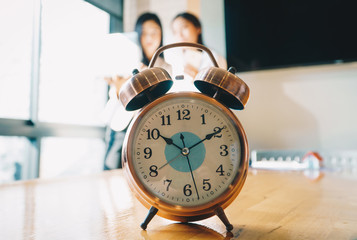 Alarm clock on white table background with business people at meeting room.Time management and...
