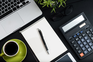 Top view, black desk with computer graph, magnifier and calculator