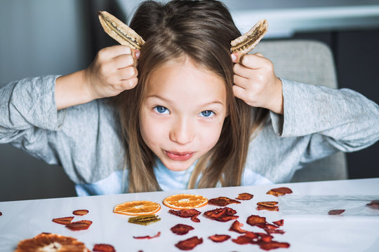 Cheeky cute blond little girl playing with dried fruit