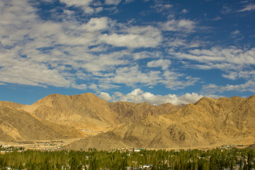 blue sky over the desert mountains and a village with trees