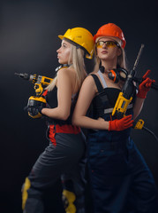 girl in construction clothes and protective equipment posing with a screwdriver