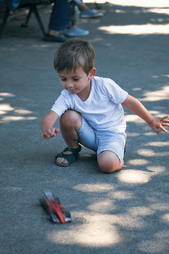 Cute boy playing with a car toy in a park in Paris, France