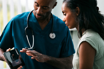 Exam: Doctor Shows Test Results On Digital Tablet
