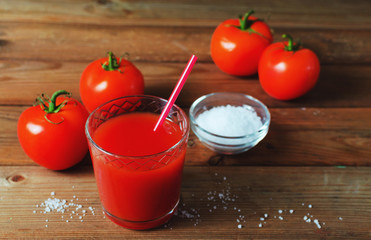 Tomato juice in glass with fresh tomatoes and salt. Rustic wooden background.