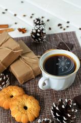 Cup of hot coffee with pastry, new year packs and pine cones
