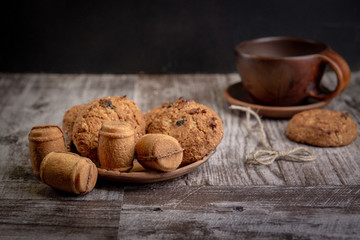 cookies lie on the table in ceramic dishes and has a variety of shapes. Ceramic brown Cup is on the table. Tea break. Copy space. Studio light. Selective focus
