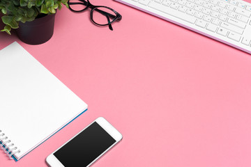 Woman's pink creative workspace with computer keyboard and supplies, top view