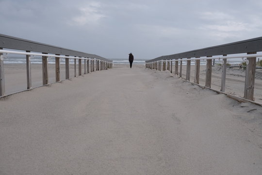 Lone figure on windy beach. 