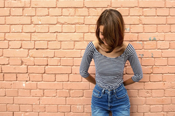 Portrait of a young girl on the background of a brick wall. No face, copy space.