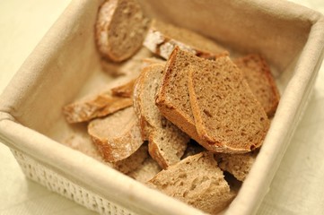 Close up of a beige textile basket full of healthy brown cereals bread