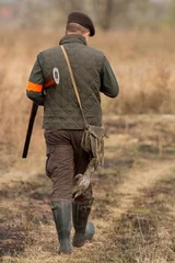 Tuinposter The hunter in the hunting clothes and with rifle hunts © predrag1