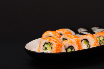 Uramaki California. Sushi rolls on a plate with black background.
