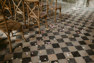 Wedding ceremony set up with wood chairs and flower petals on vintage 1900s checkered floor tile