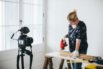 Female blogger ​​​​​​​​​​​​​​cutting a plank with a jigsaw machine