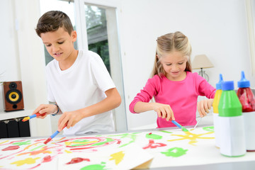Obraz na płótnie Canvas two beautiful young kids boy and girl hand painting on a white paper with color paint