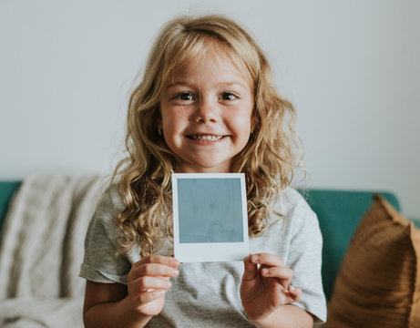 Little girl showing a photo from an instant camera
