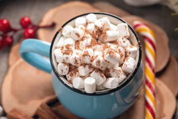 Mug of hot chocolate with marshmallow on top and Lollipop stick on wooden background. Cozy warm winter composition